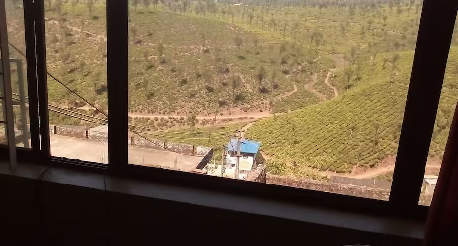 Window view overlooking emerald Valparai tea plantations and hillside